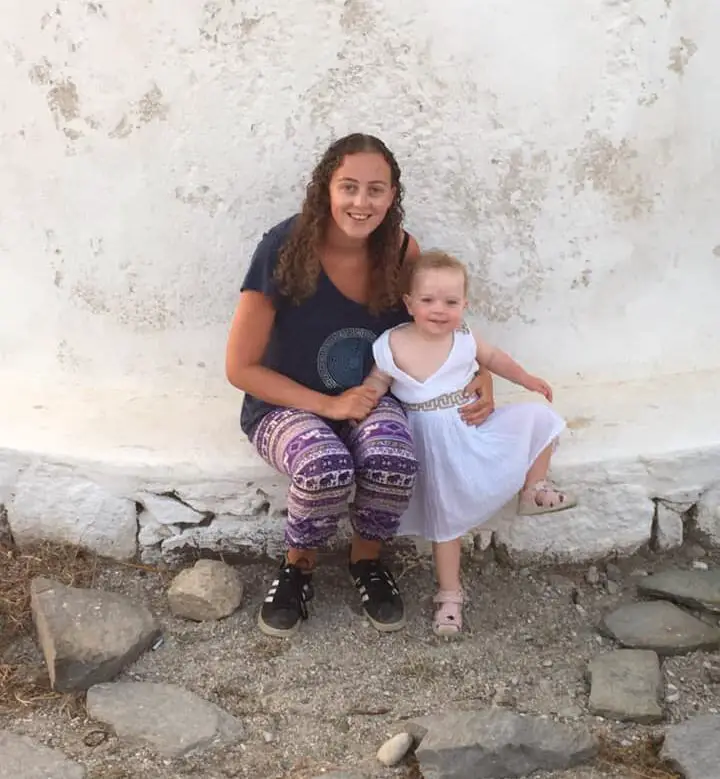 The author and founder of the island hopping in Greece blog with her 1 year old daughter by the Mykonos windmills.