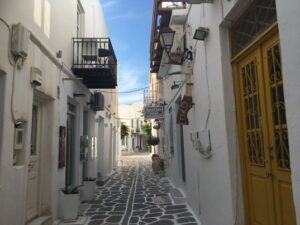 Narrow alley in Paros, showcasing traditional Cycladic architecture with white walls and colorful doors, inviting exploration.