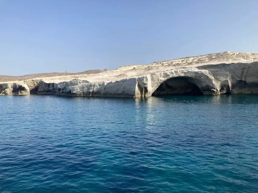 Sarakiniko Beach on Milos with its unique white volcanic rock formations creating natural arches over clear blue waters, resembling a moonscape against the sea.