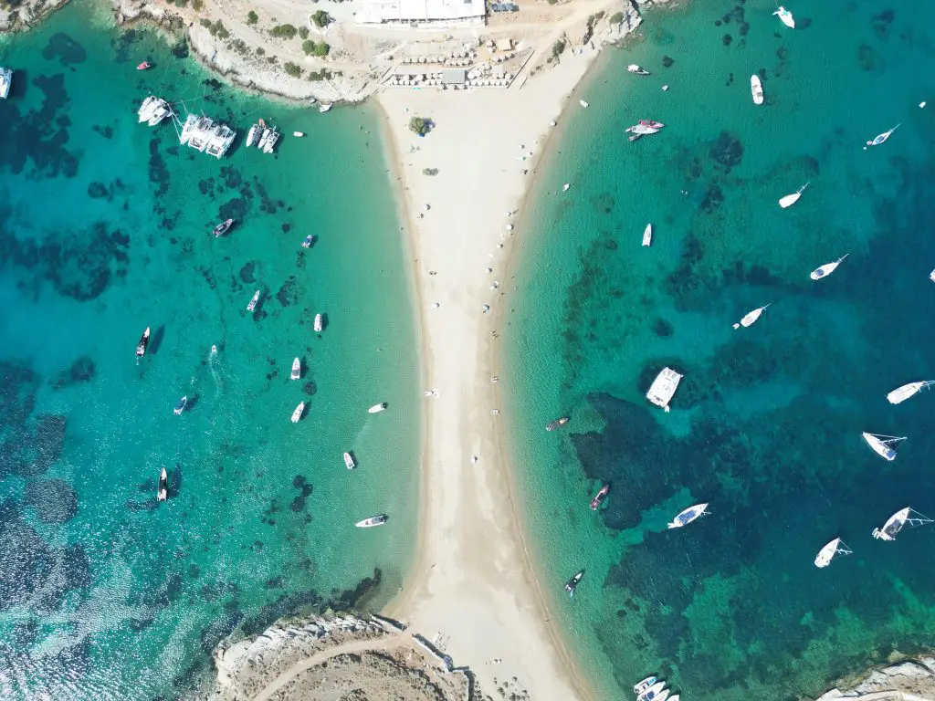 A stunning aerial view of Kythnos, Greece, showcasing a sandy beach, turquoise waters, and anchored boats.